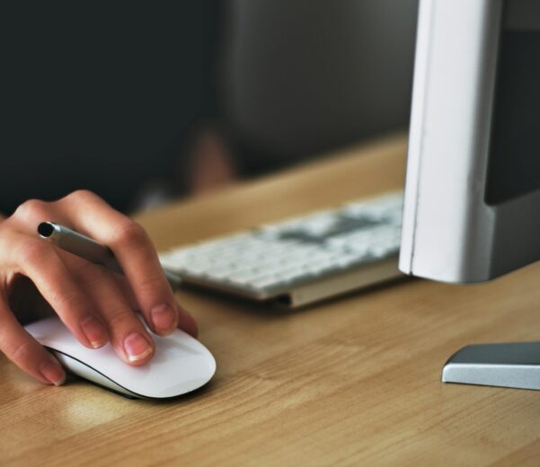Free A hand using a wireless mouse at a modern desk setup with a computer and keyboard. Stock Photo