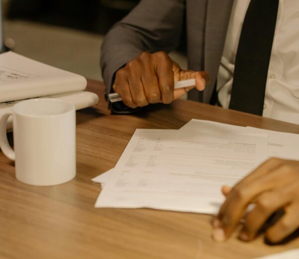 Free Close-up of a businessman holding and reviewing documents on a wooden desk. Stock Photo