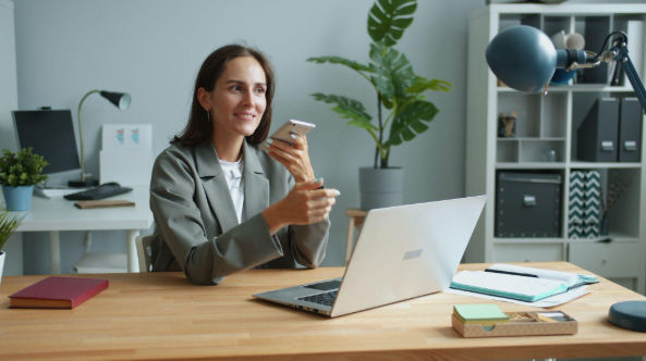 lady holding phone while working on a laptop
