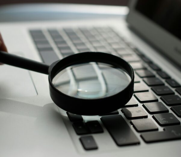 magnifying glass near gray laptop computer